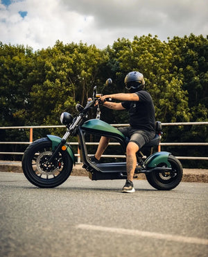 E-Chopper HL 6.0 Phantom in Grün – Seitenansicht mit Fahrer im Stand, Lifestylefoto auf Straße im Sommer